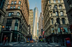 Street view of One World Trade Center in New York City surrounded by urban architecture and city life.