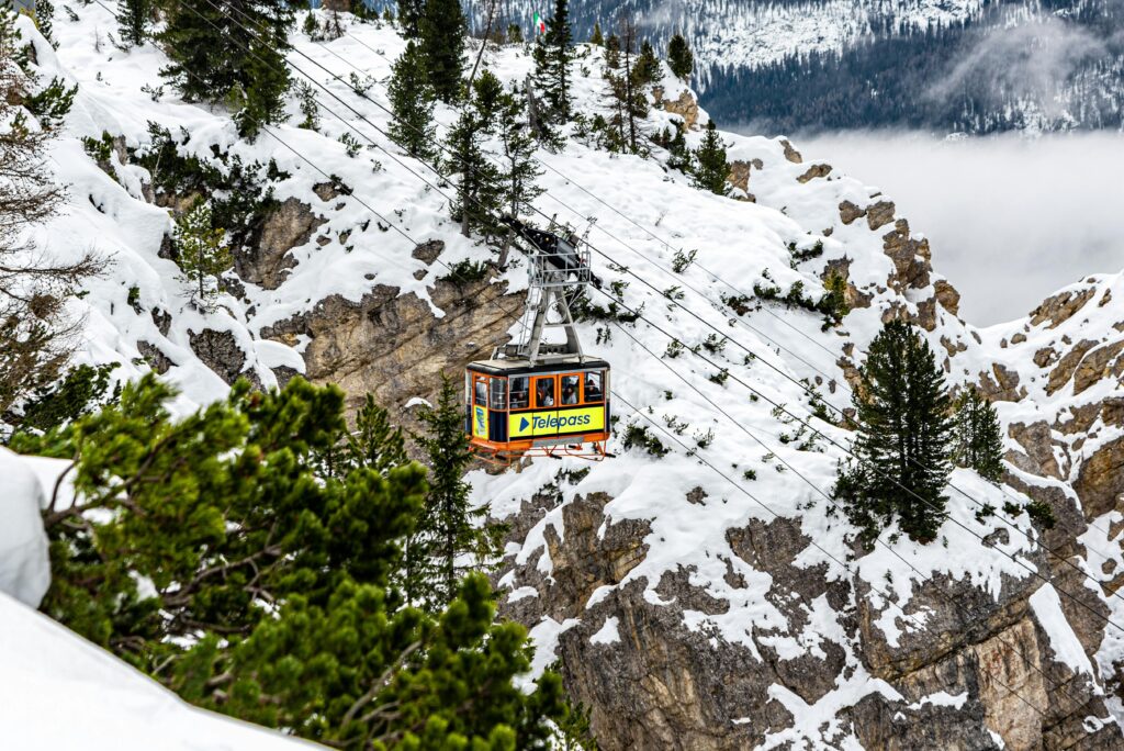 Cable car navigating snowy cliffs in Cortina d'Ampezzo, Italy during winter.