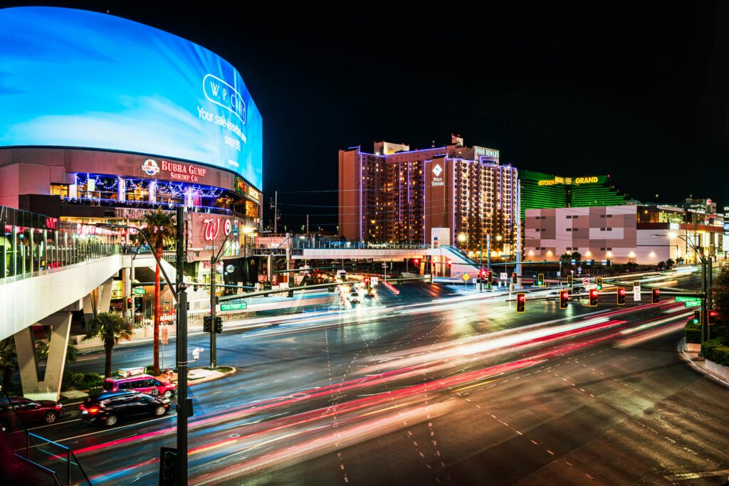 Dynamic night view of Las Vegas Boulevard featuring light trails and vibrant city lights.