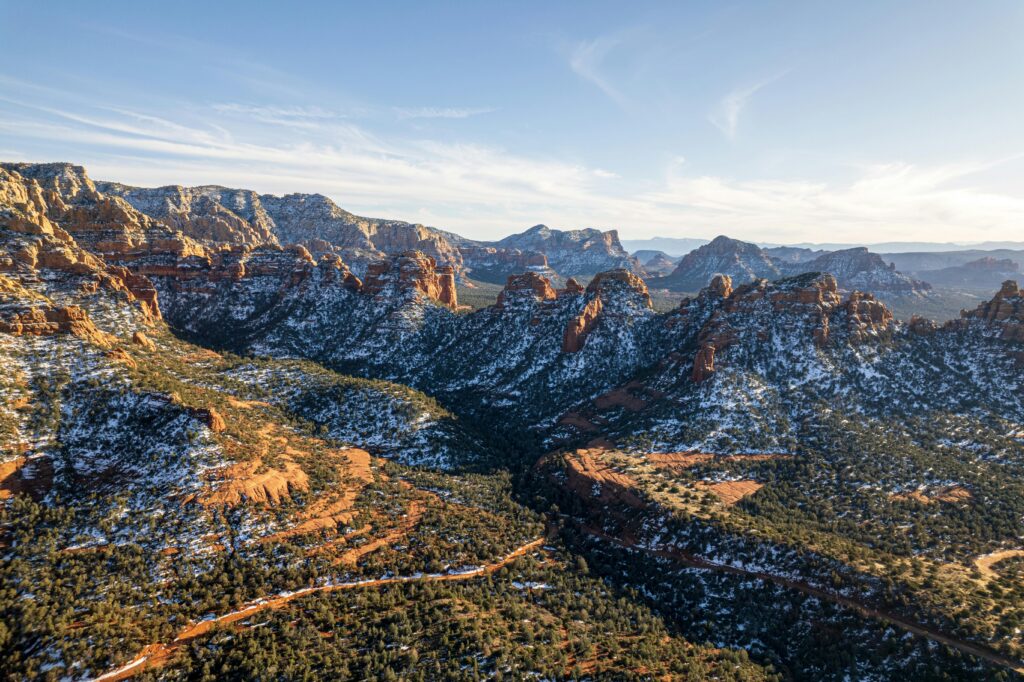 Stunning aerial shot of snow-covered Sedona red rock formations under a clear sky.