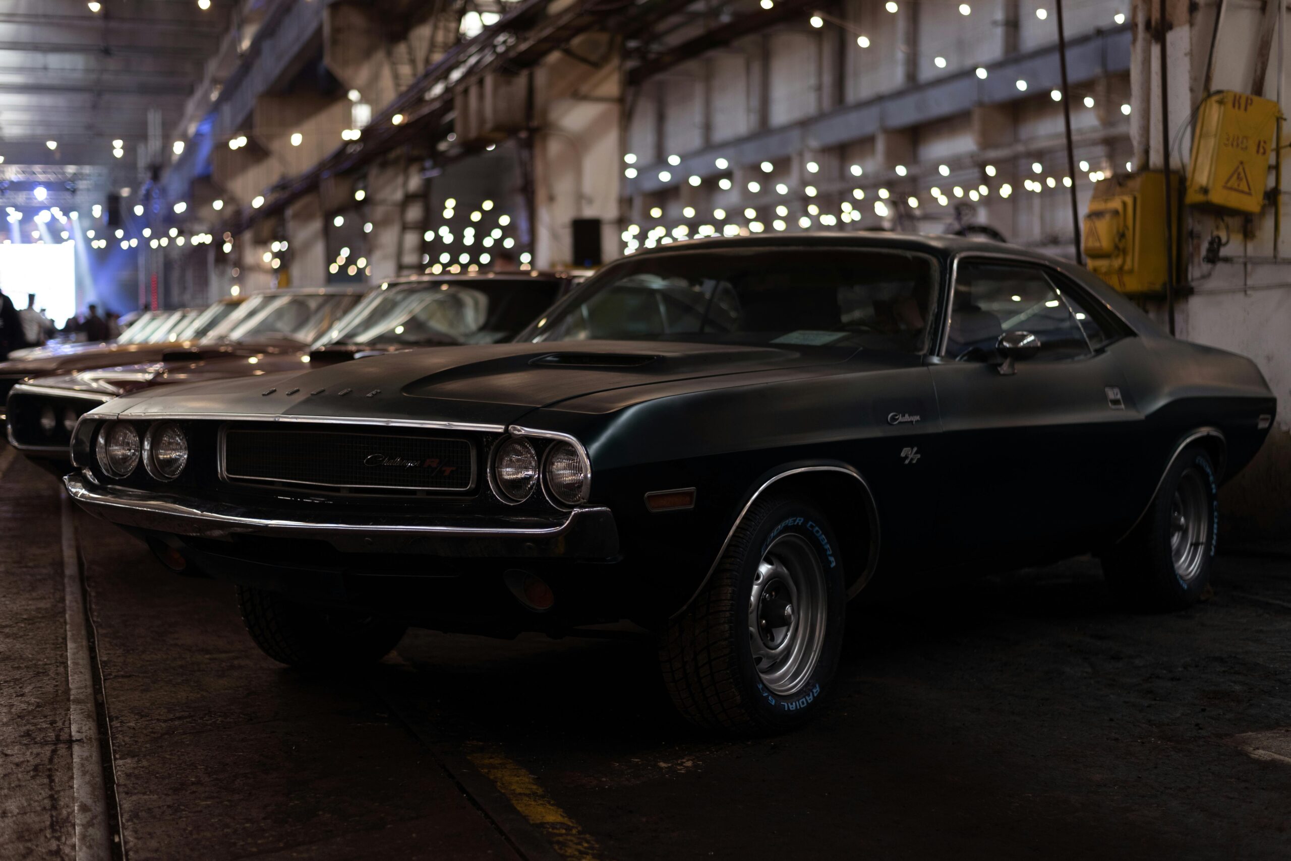 Vintage black Dodge Challenger parked in an industrial garage setting, evoking nostalgia and classic car elegance.