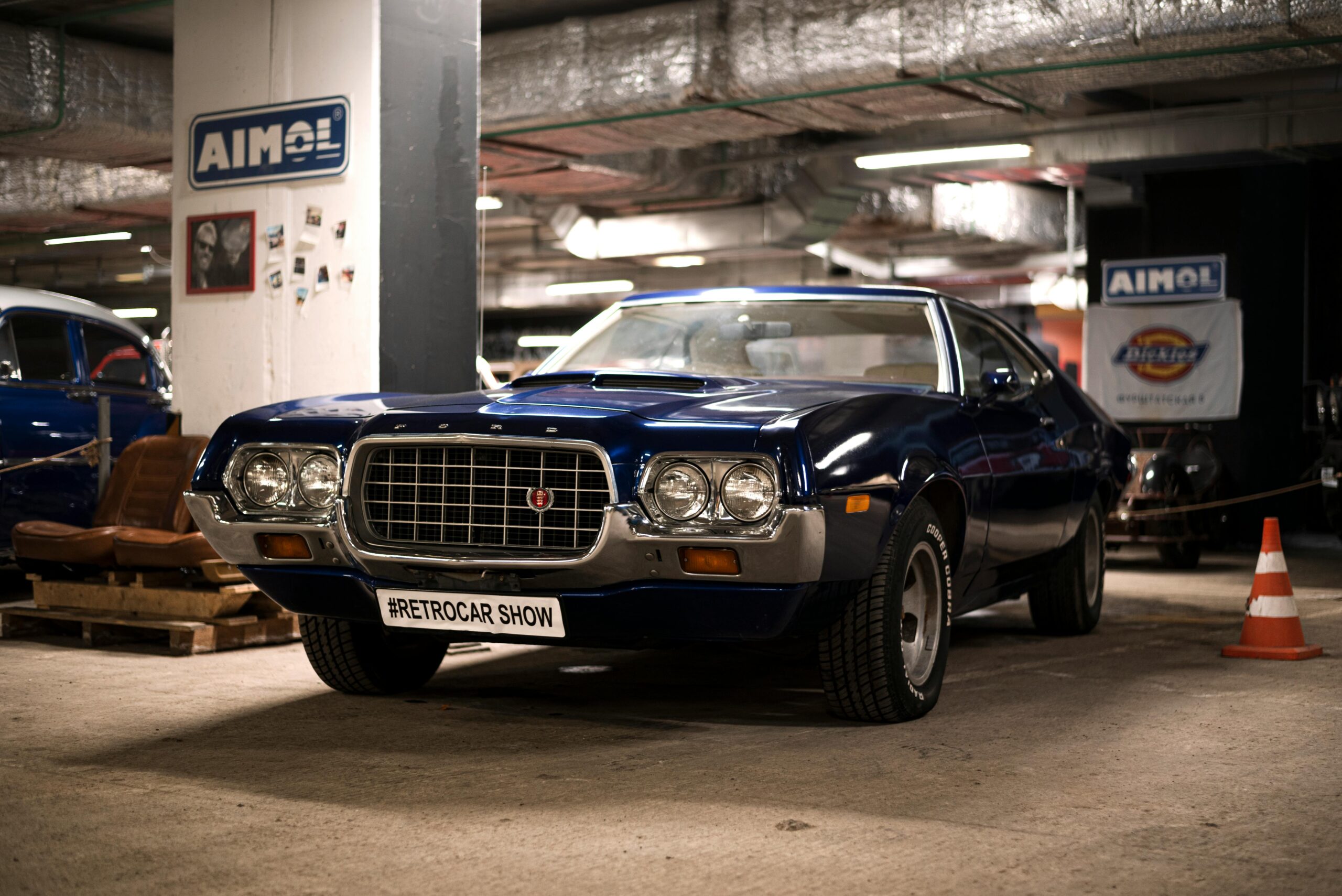Blue Ford Gran Torino on display at an indoor retro car show, showcasing vintage automotive design.