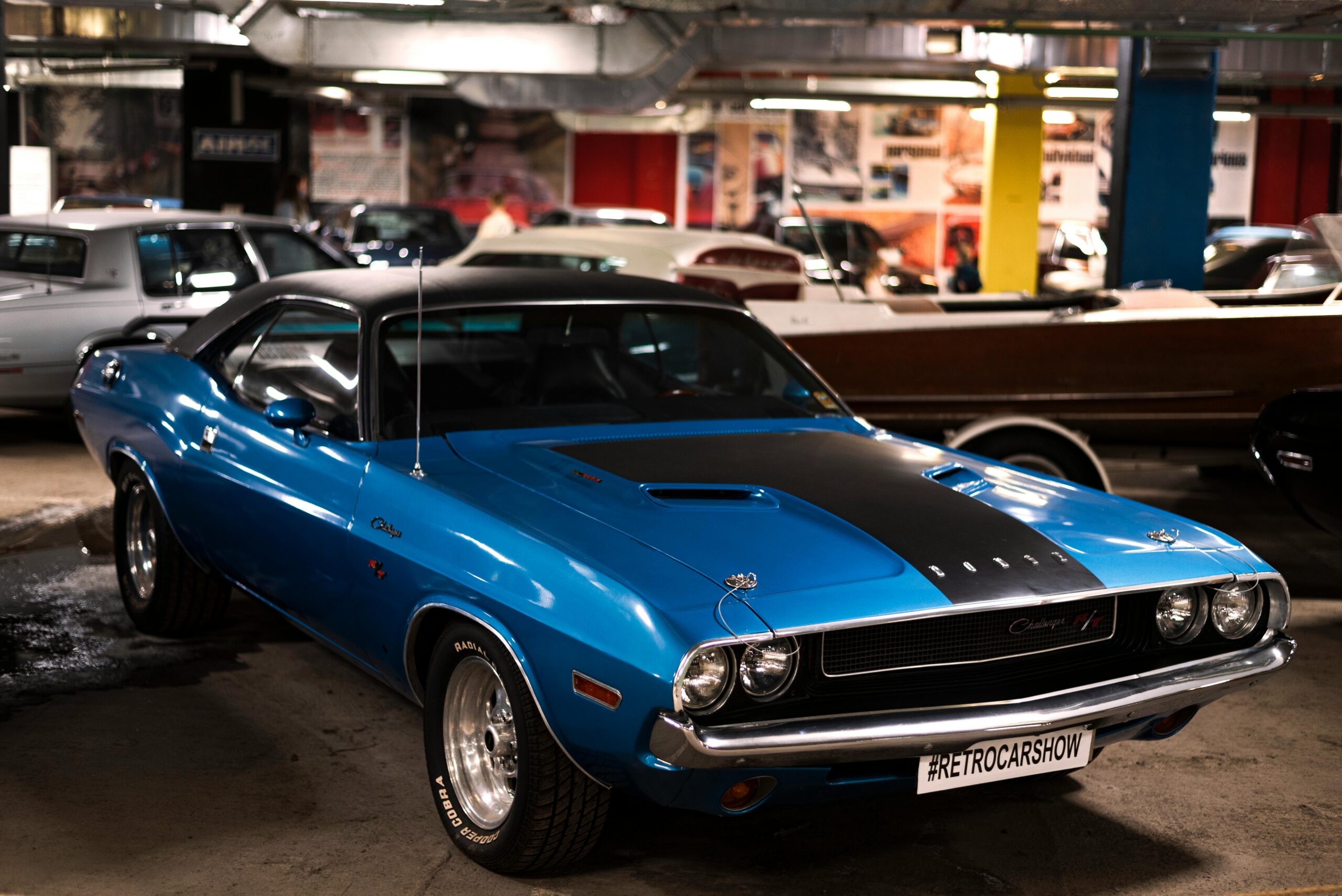 Classic blue Dodge Challenger parked in a car show garage.