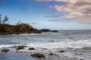 A tranquil rocky beach with waves under a partly cloudy sky, perfect for scenic inspiration.