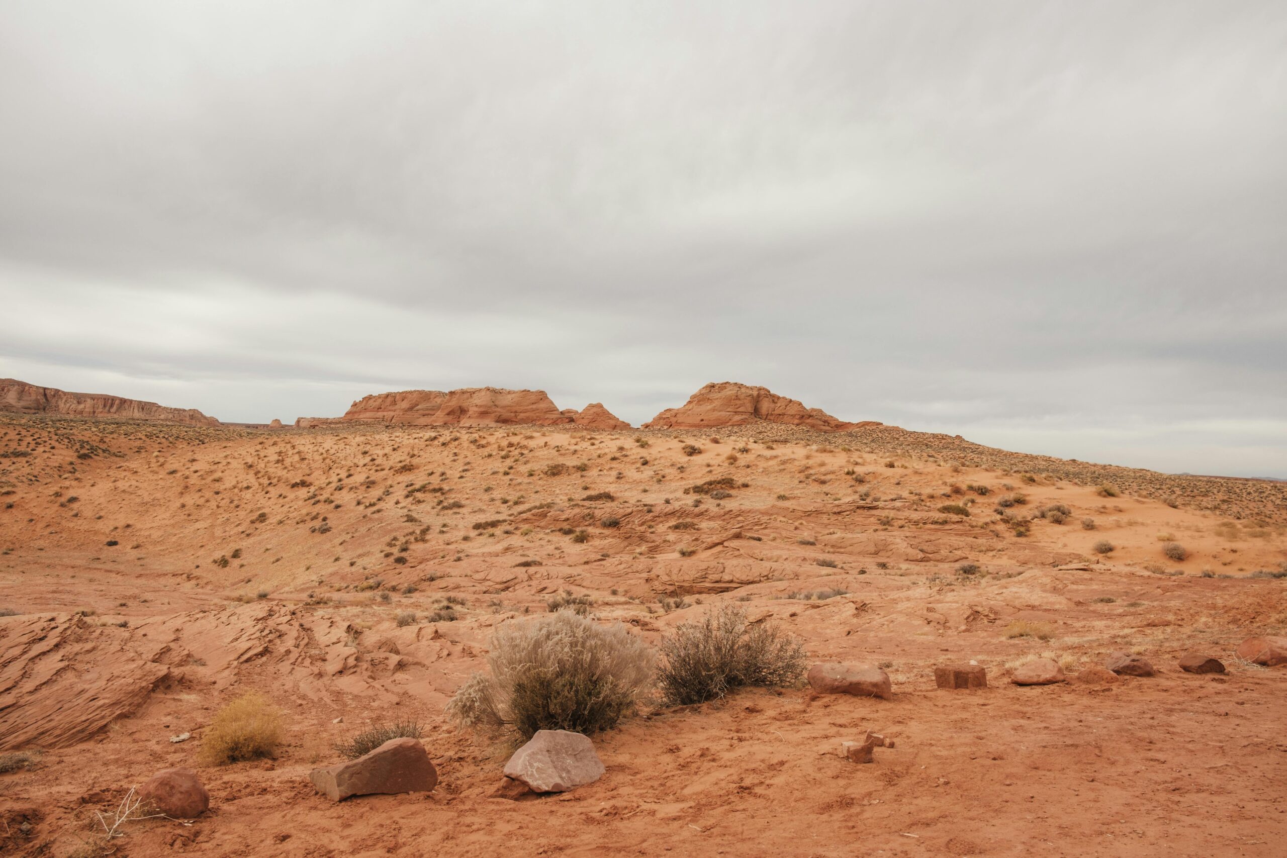Explore Arizona's breathtaking desert landscape with red rock formations under a vast, cloudy sky.