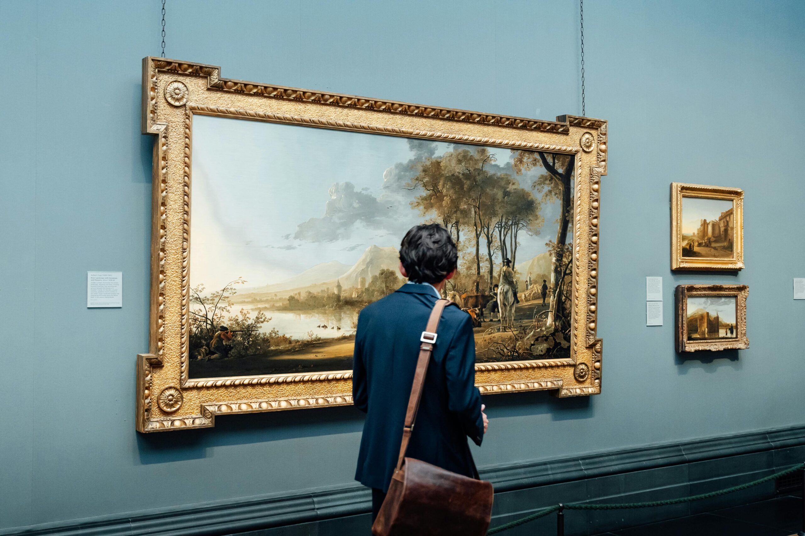 A man admires a large framed painting in an art gallery, England.