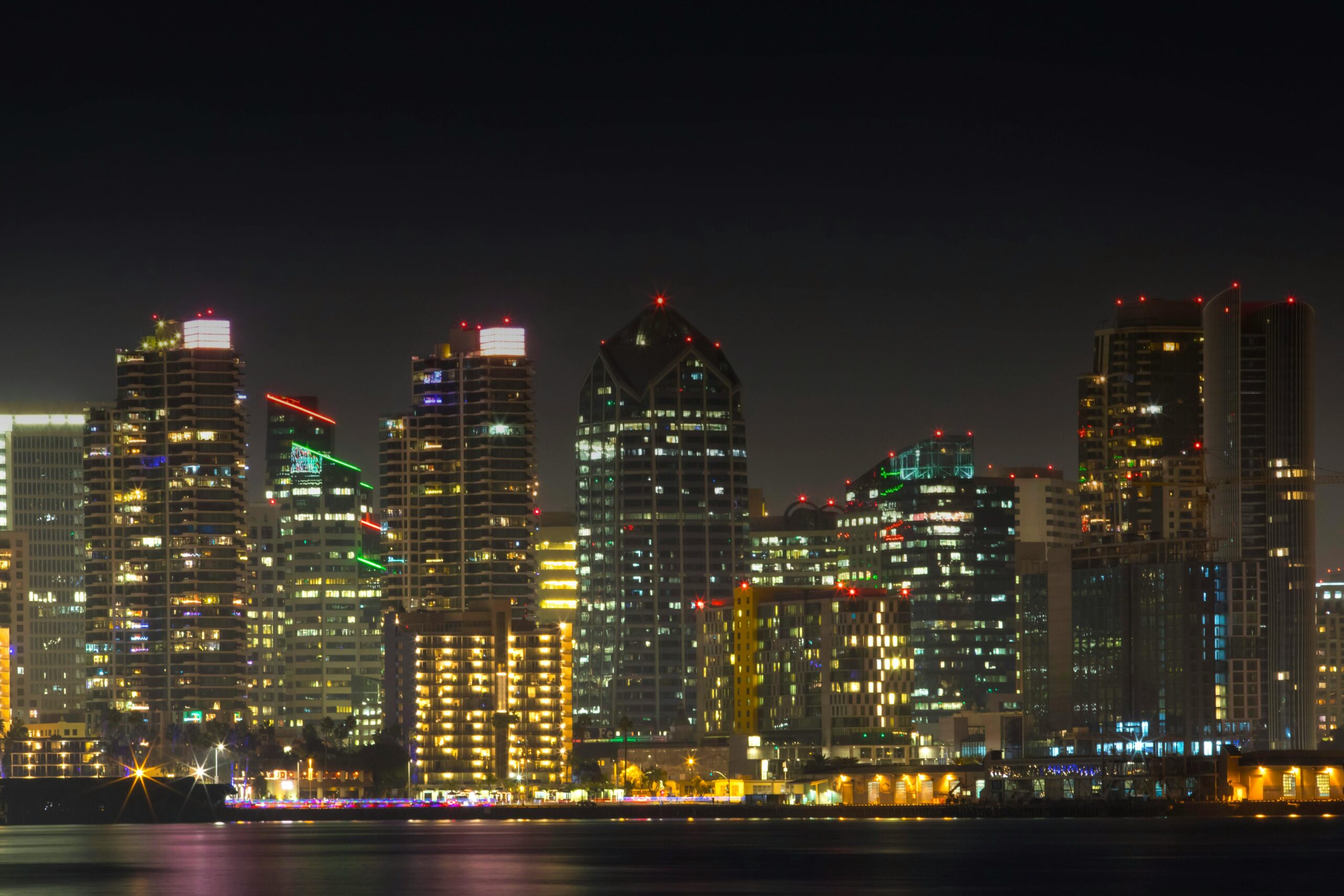 Stunning view of San Diego's illuminated skyline at night with city lights reflecting on the water.