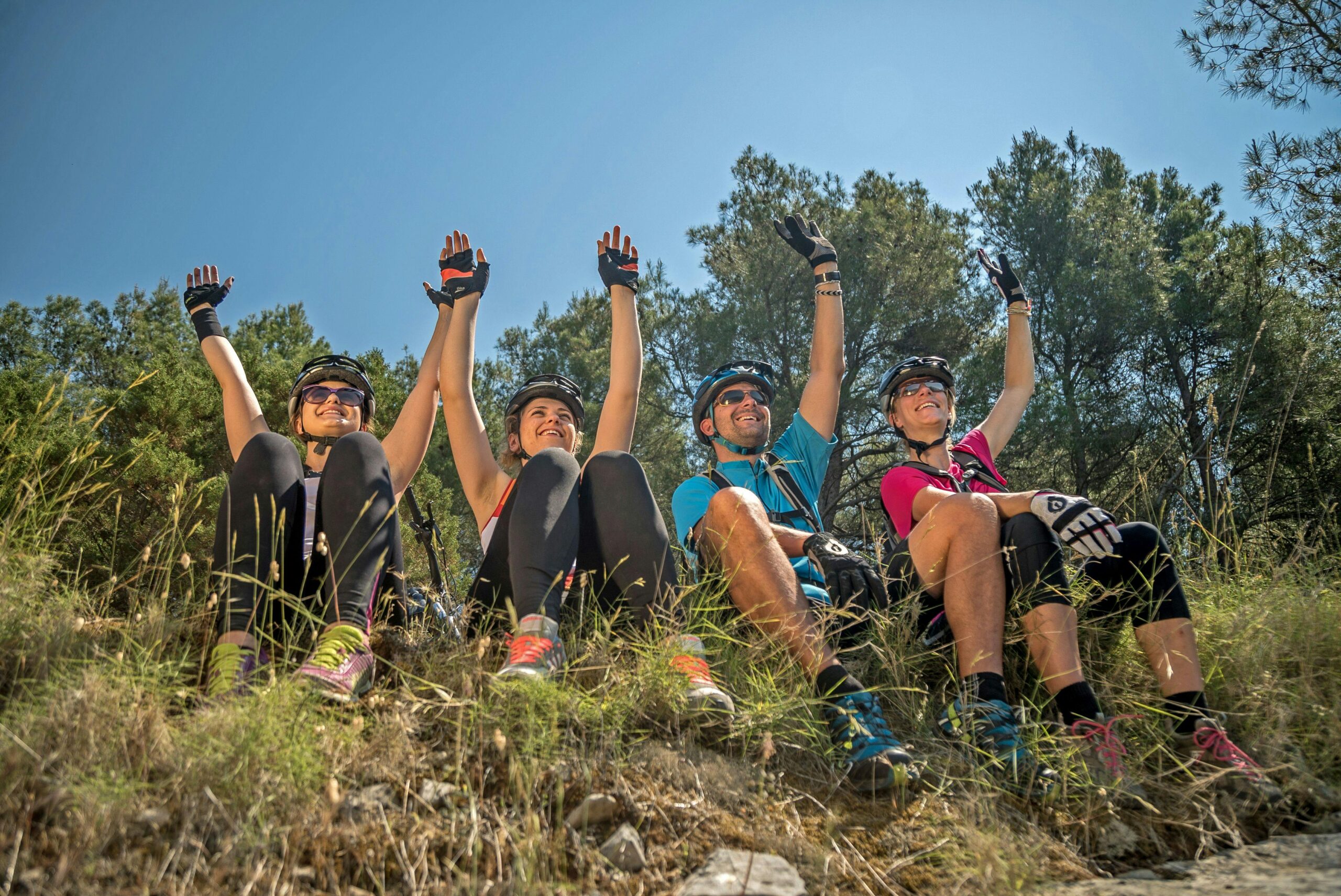 Happy group of cyclists taking a break and celebrating outdoors on a sunny day.