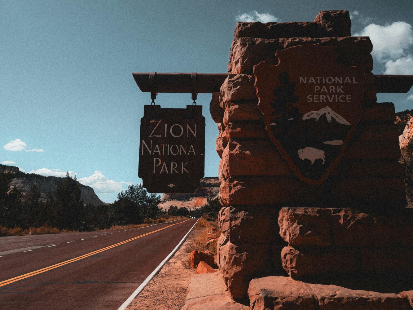 Explore Zion National Park with its iconic entrance sign along a picturesque road in Utah.
