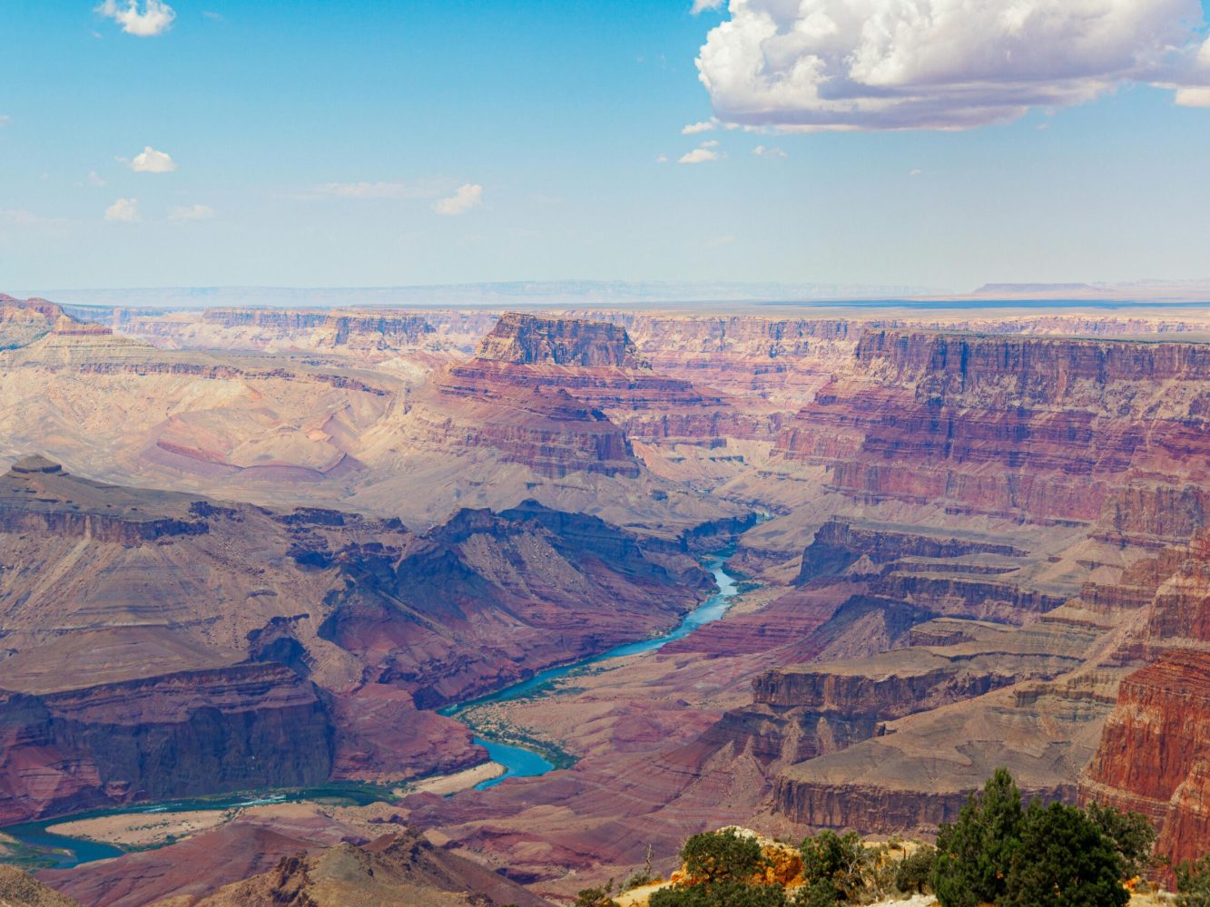Stunning panorama of the Grand Canyon with the Colorado River under a blue sky.